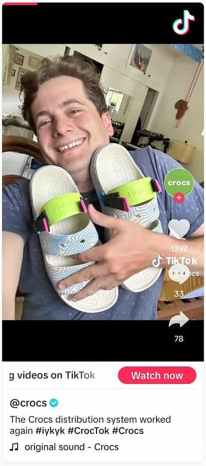 Image 13: Video from Crocs showing a person holding a pair of Crocs to their chest and smiling at the camera