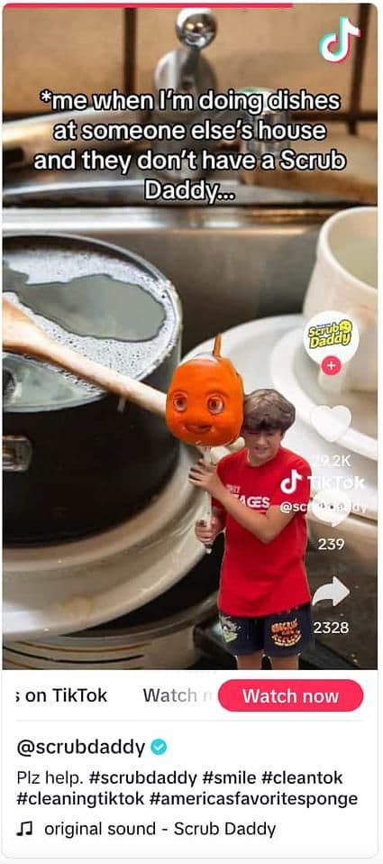 Image 5: Scrub Daddy TikTok video showing someone holding up a fish-shaped sponge against a green screen background of a pile of dirty dishes
